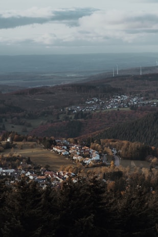 A sunlit village landscape blending traditional homes with solar panels and wind turbines.