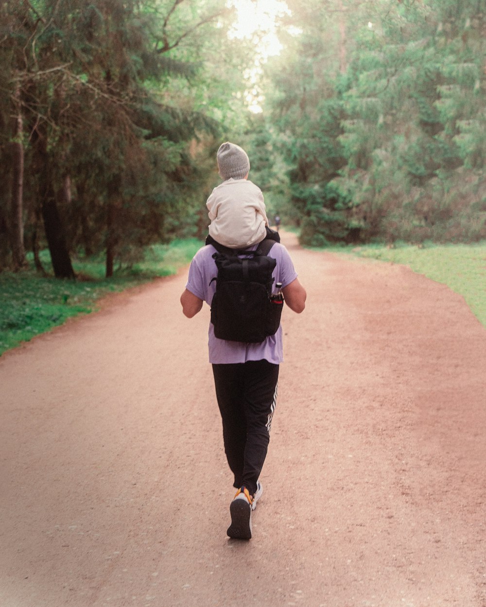 a person with a backpack walking down a dirt road