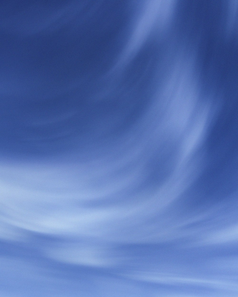 a plane flying through a blue sky with white clouds