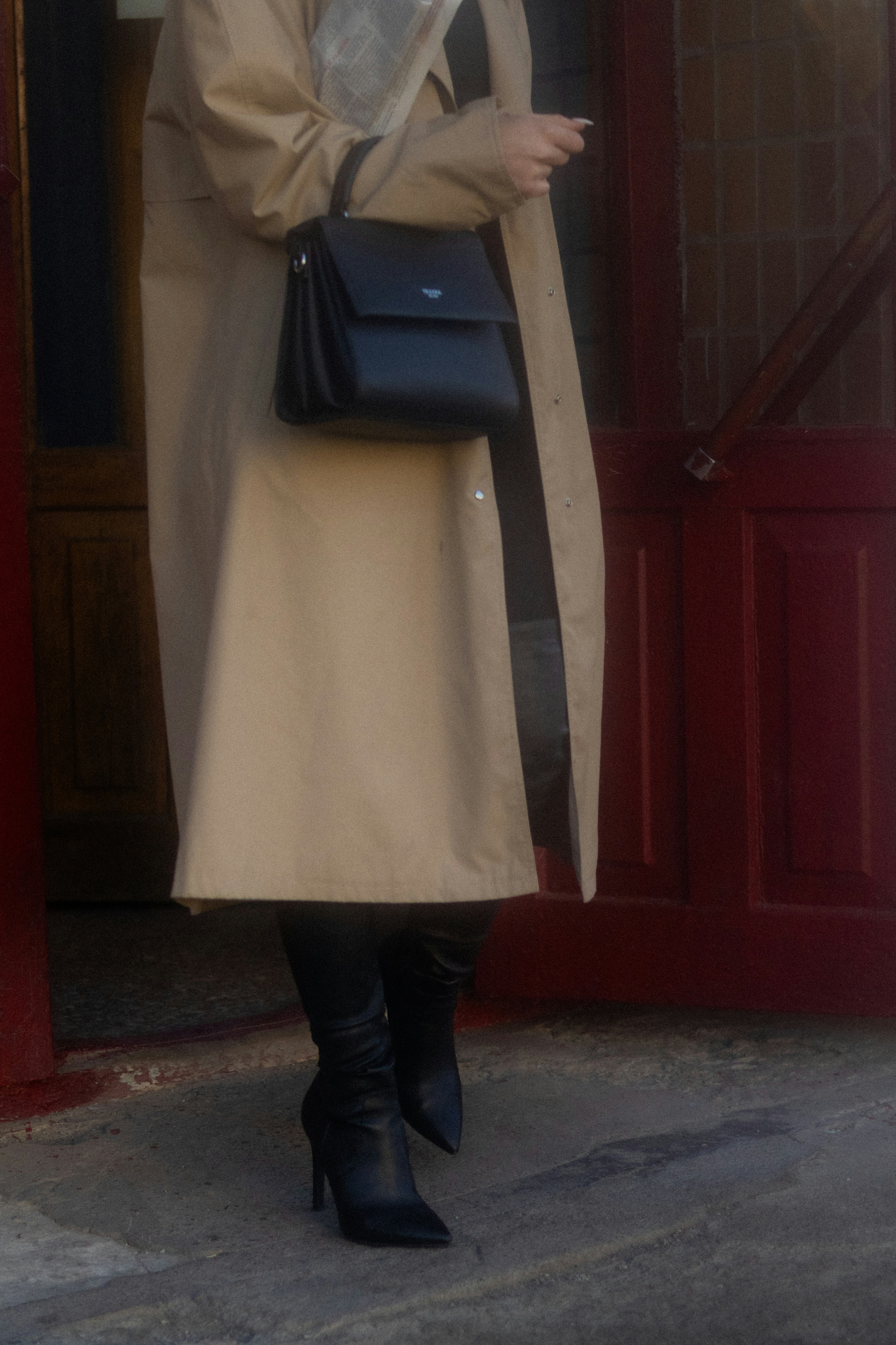 トレンチコートを着て黒いハンドバッグを持った女性