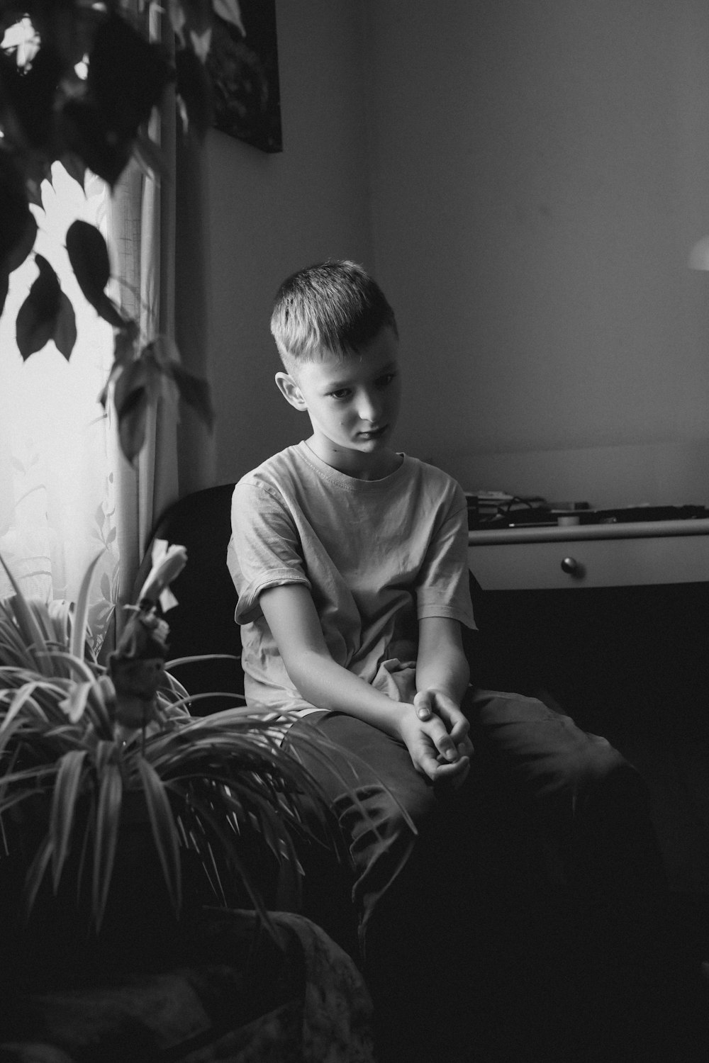 a black and white photo of a boy sitting on a couch