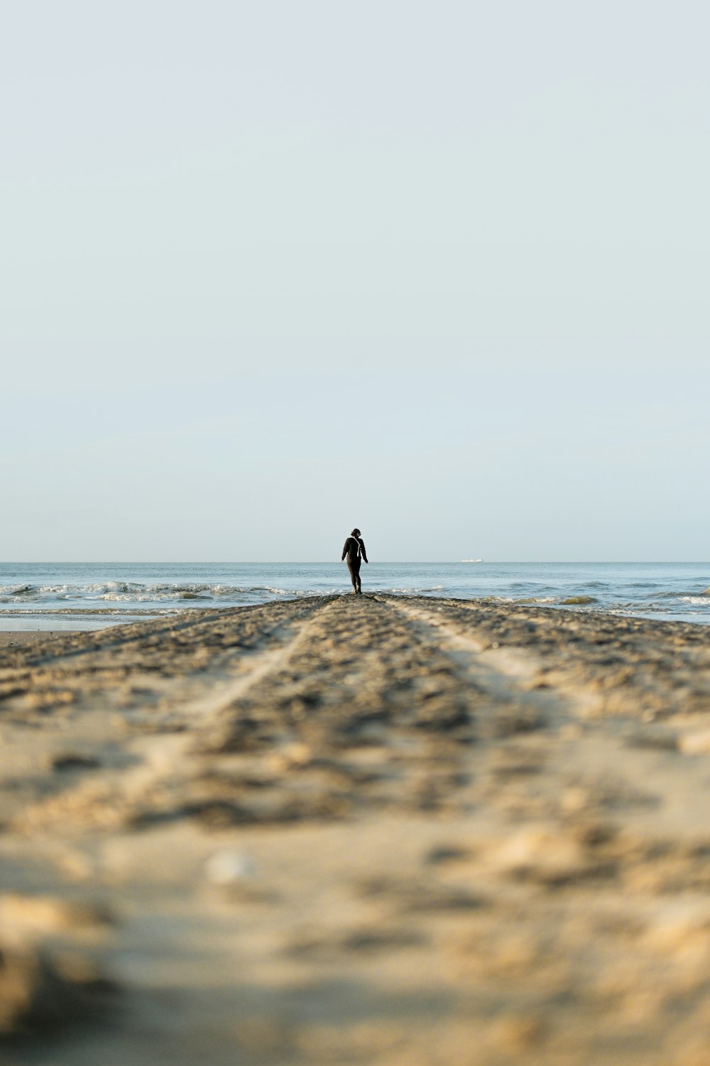 a lone person walking on a beach near the ocean