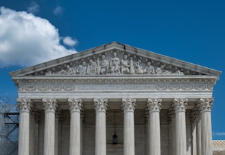 The image presents the facade of a neoclassical building with grand columns and intricate sculptures atop the pediment. The structure is made of stone, and the frieze bears the inscription 'EQUAL JUSTICE UNDER LAW.'
