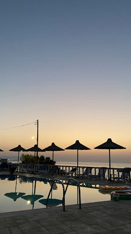Sunset view over the serene seaside pool with loungers and soft lighting.