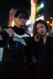 Nocturna posing together with serious expressions against a dark urban backdrop.