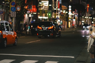 A city street with cars and people using a ride-sharing app on their phones