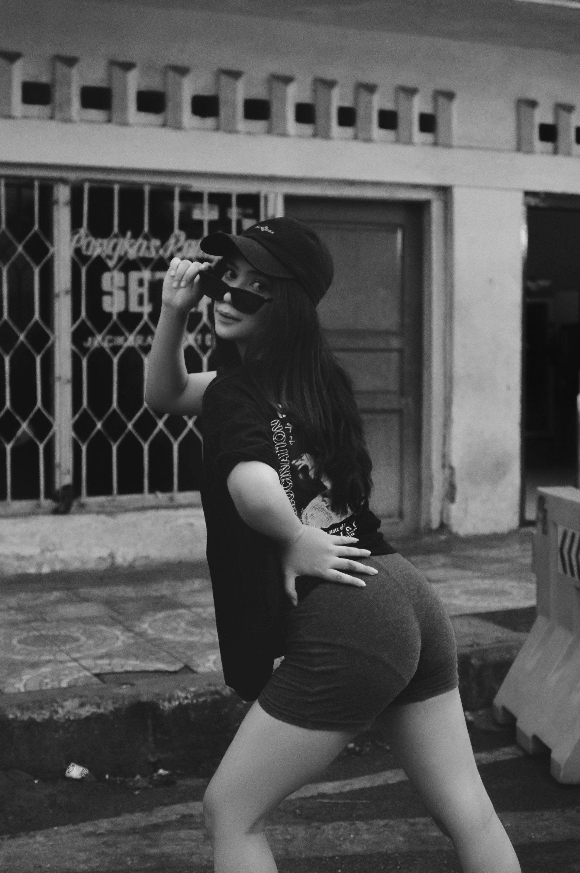 A stylish young person wearing urban streetwear, posing confidently against a vibrant city backdrop.