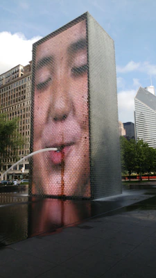 A high-tech water fountain featuring LED lights and a digital display, with a cat watching.