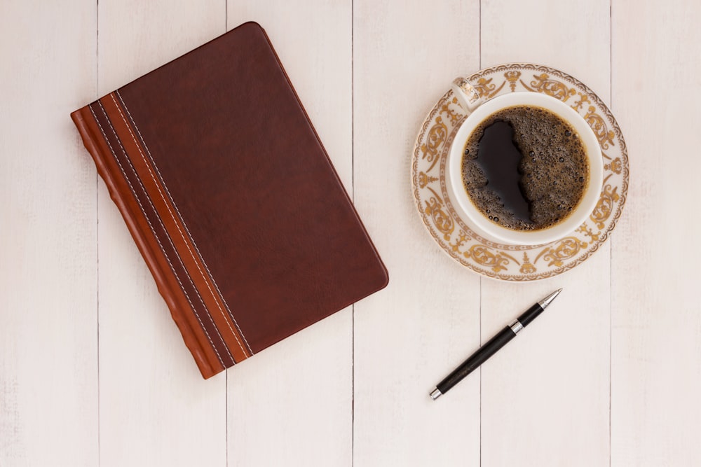 a cup of coffee next to a notebook and pen