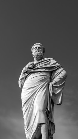 A black and white portrait of a classic philosopher statue against a light background.