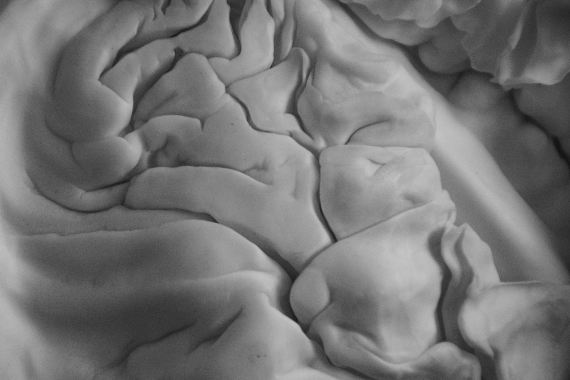 An intimate close-up of textured fabric folds, emphasizing subtle contrasts and gentle curves in monochrome.