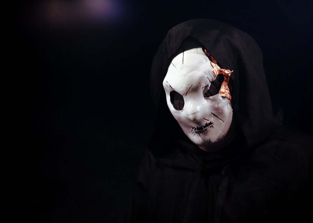 a person wearing a white mask and a black hood
