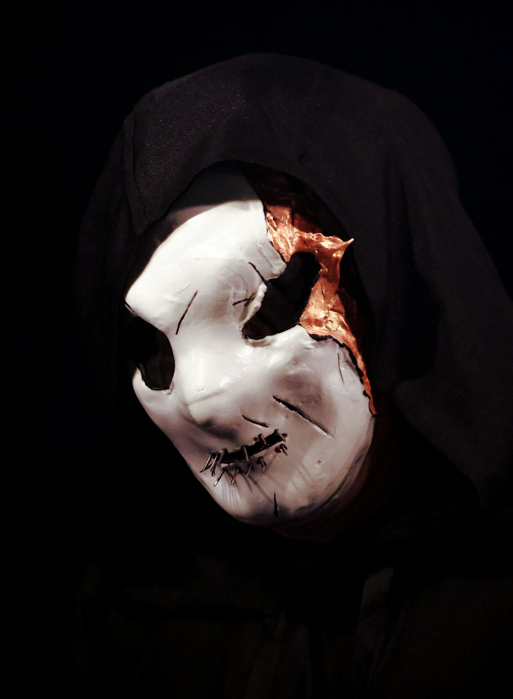 a person wearing a white mask and black hood