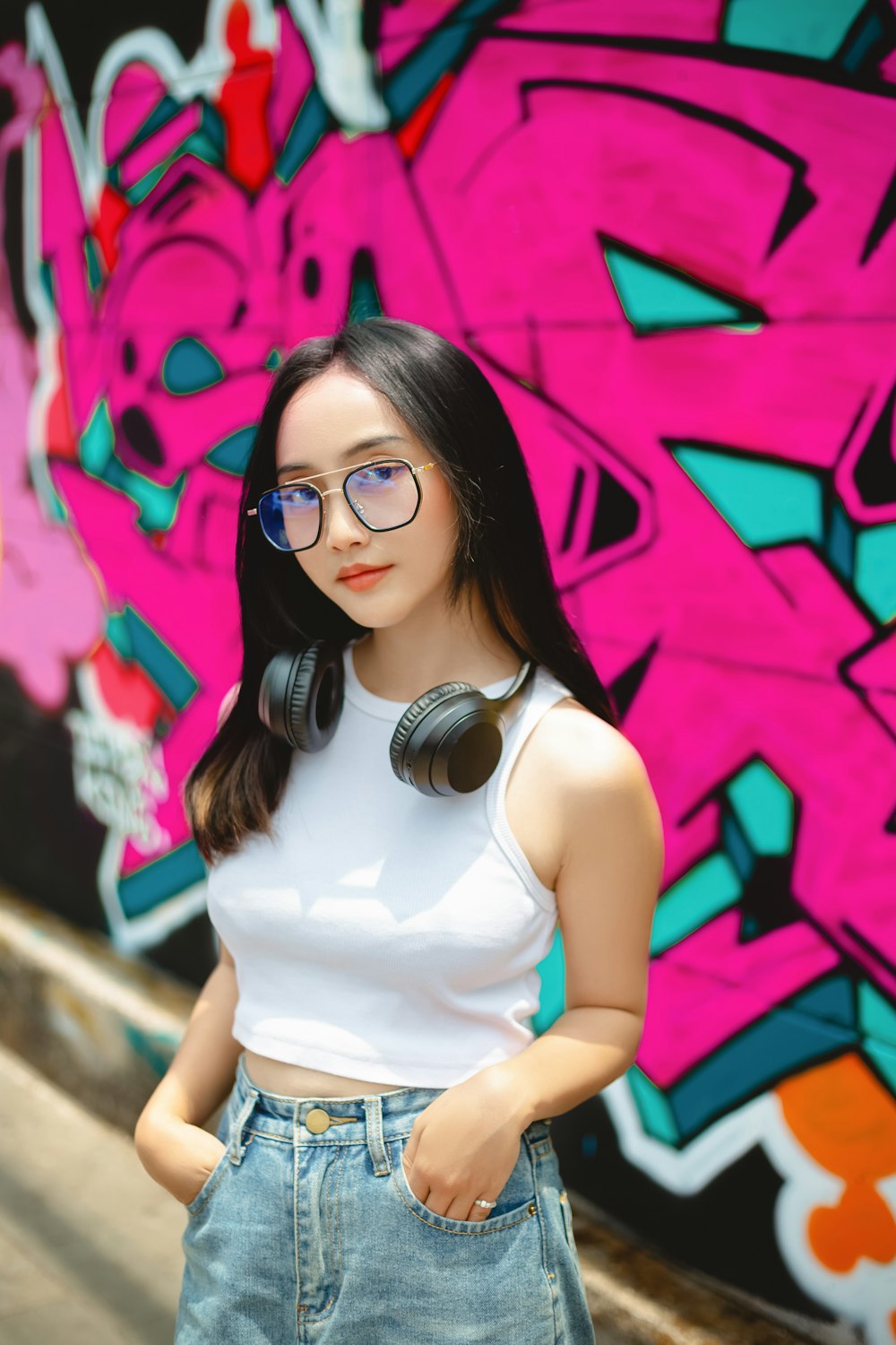 a doll wearing headphones standing in front of a graffiti wall