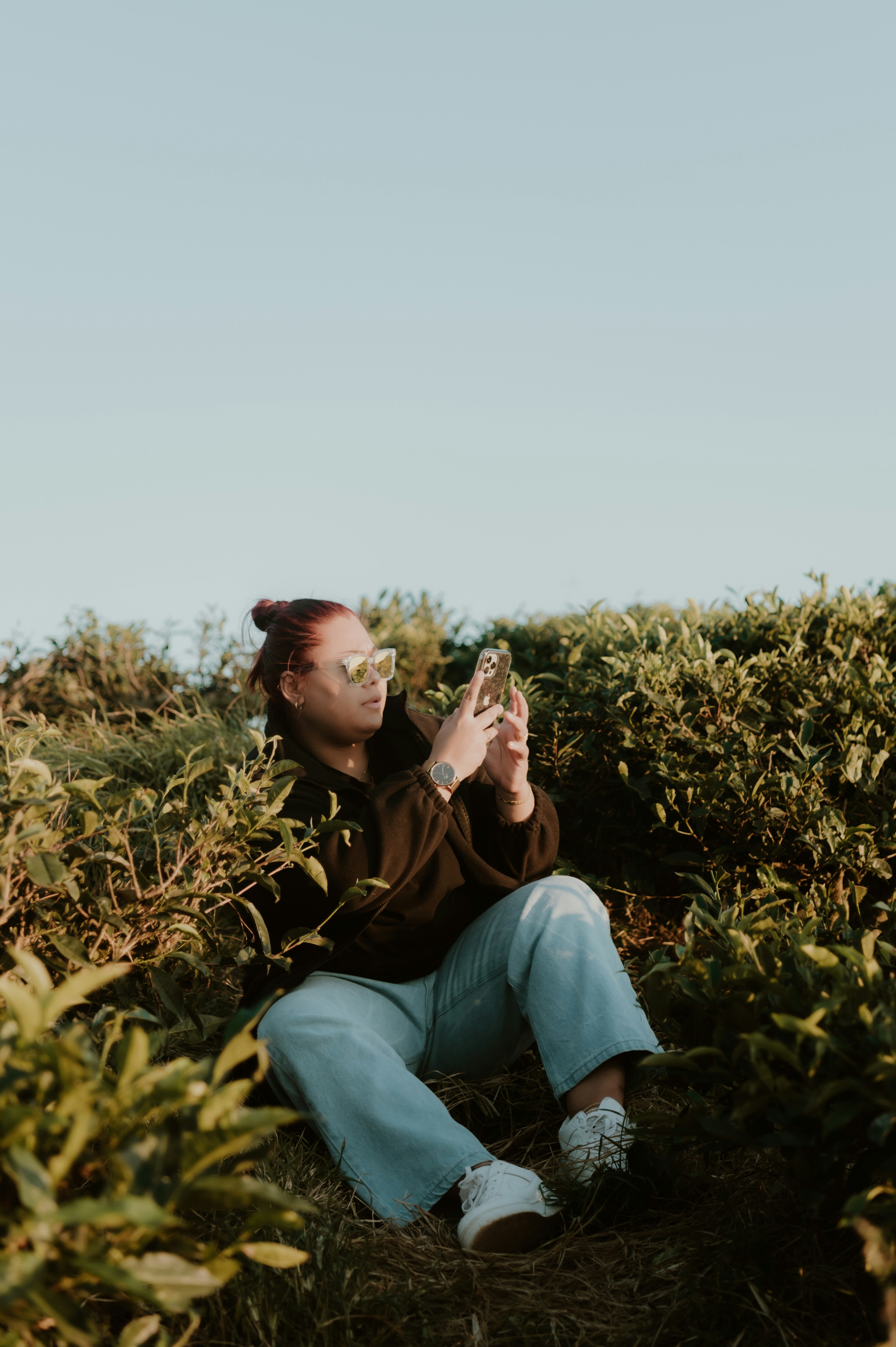 a woman sitting on the ground in a field