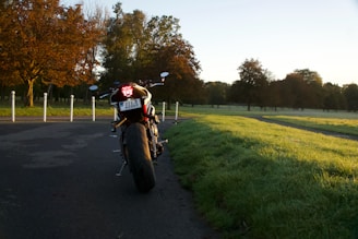 A motorcycle parked on a dirt path surrounded by autumn trees with golden leaves.