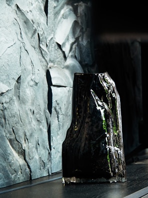 Close-up of a sleek matte black 3D printed vase with intricate geometric patterns.