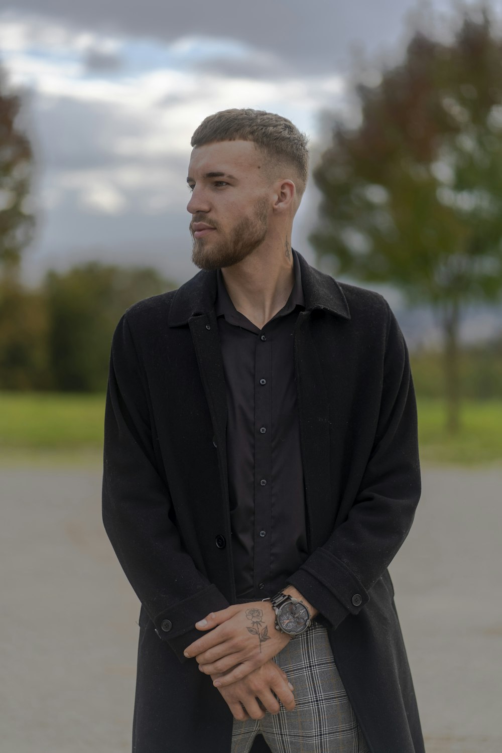 a man standing in a parking lot with his hands in his pockets