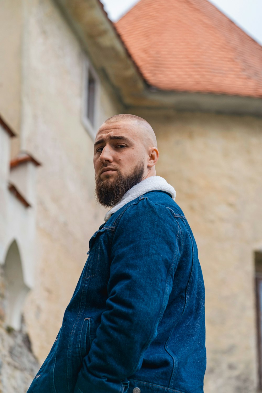 a man with a goatee and a beard standing in front of a building