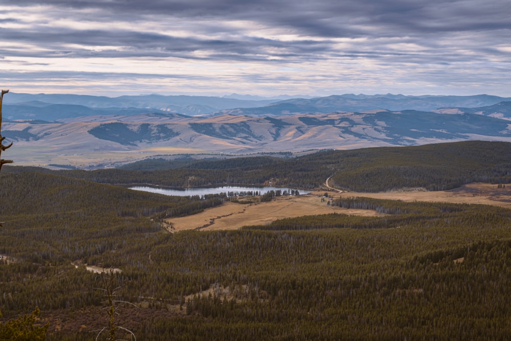 a view of a valley with a lake and mountains in the background