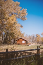 A cozy Poconos cabin surrounded by autumn trees under a clear blue sky.