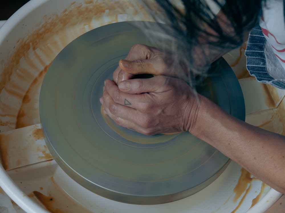 a person is spinning a piece of pottery on a wheel