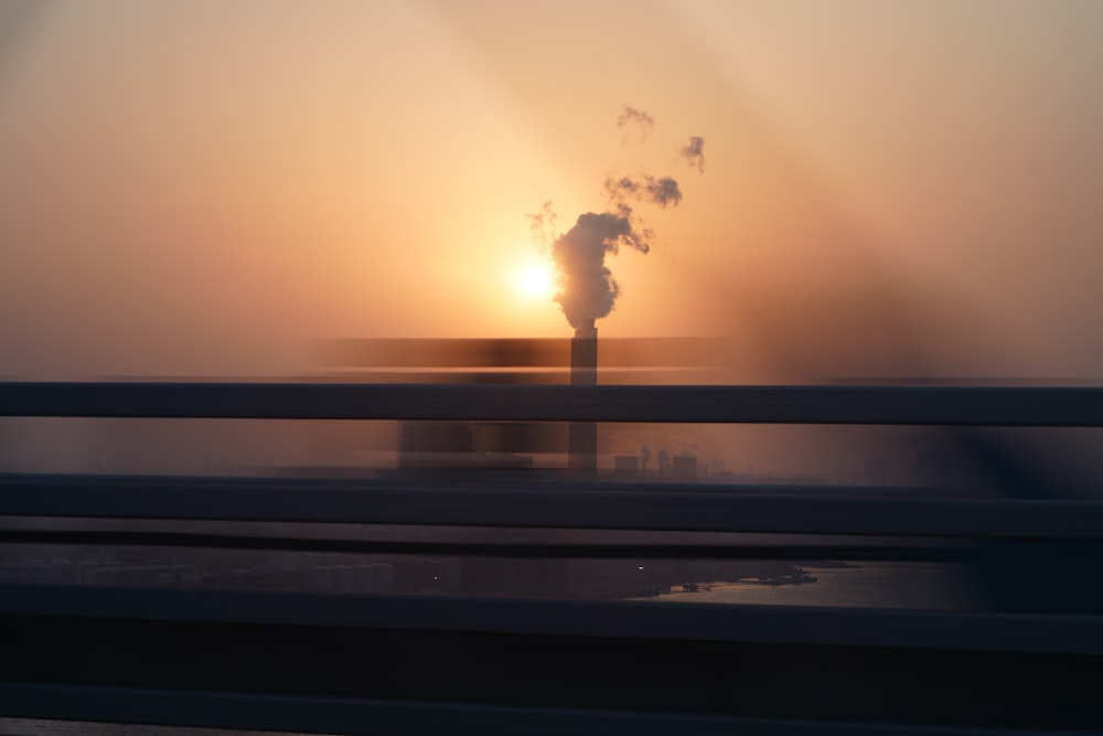 the sun is setting behind a smokestack on a bridge