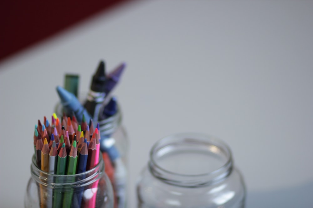 a jar of colored pencils sitting next to a jar of colored pencils