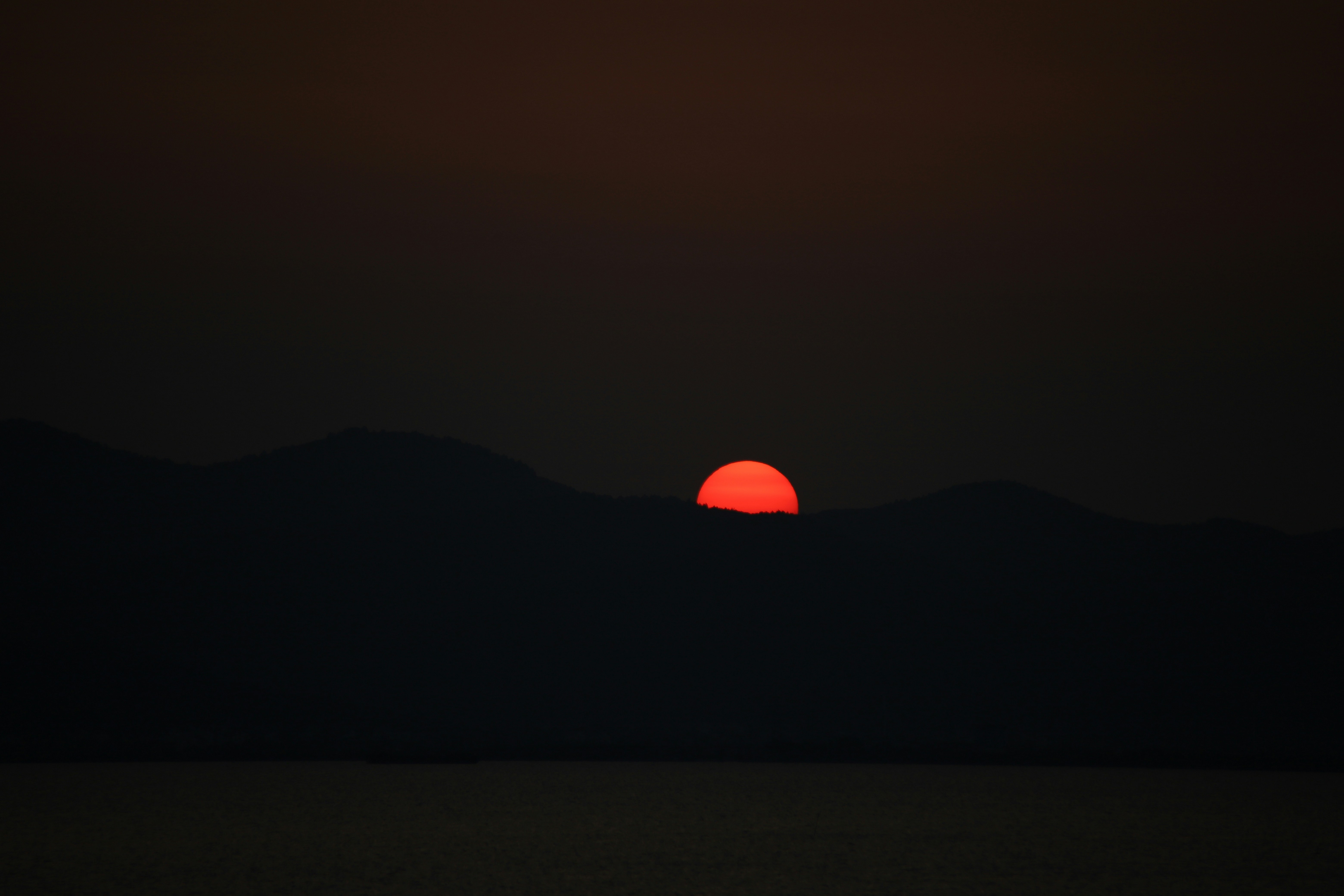 the sun is setting over a mountain range
