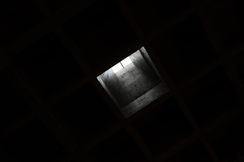 a window in a dark room with a light coming through it