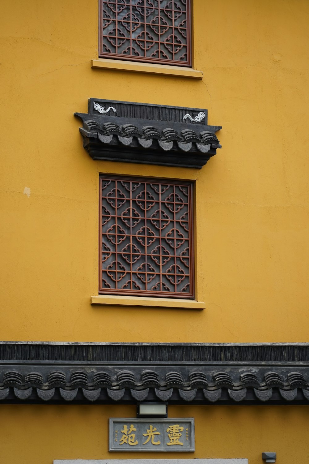 a yellow building with two windows and a sign