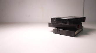 A stack of three VHS tapes placed on a plain, light-colored surface. The tapes are marked with a code and 'Made in Japan' text. The composition is simple, with minimalistic lighting casting soft shadows.