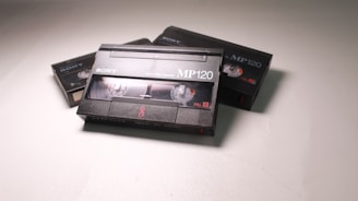 A collection of vintage video cassette tapes with the 'Sony' brand. The central focus is on a prominently displayed MP120 tape, with others partially visible in the background. The tapes feature clear spools and are labeled with 'PAL' and '8'.