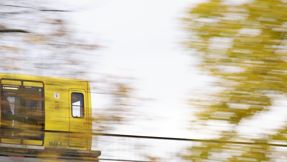 a yellow train traveling down train tracks next to a forest