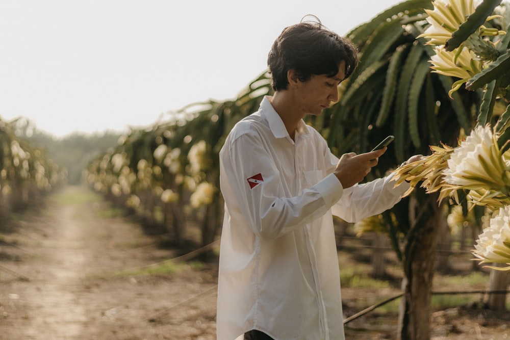 um homem parado em um campo de banana segurando um telefone celular