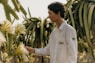 a man standing next to a bunch of flowers