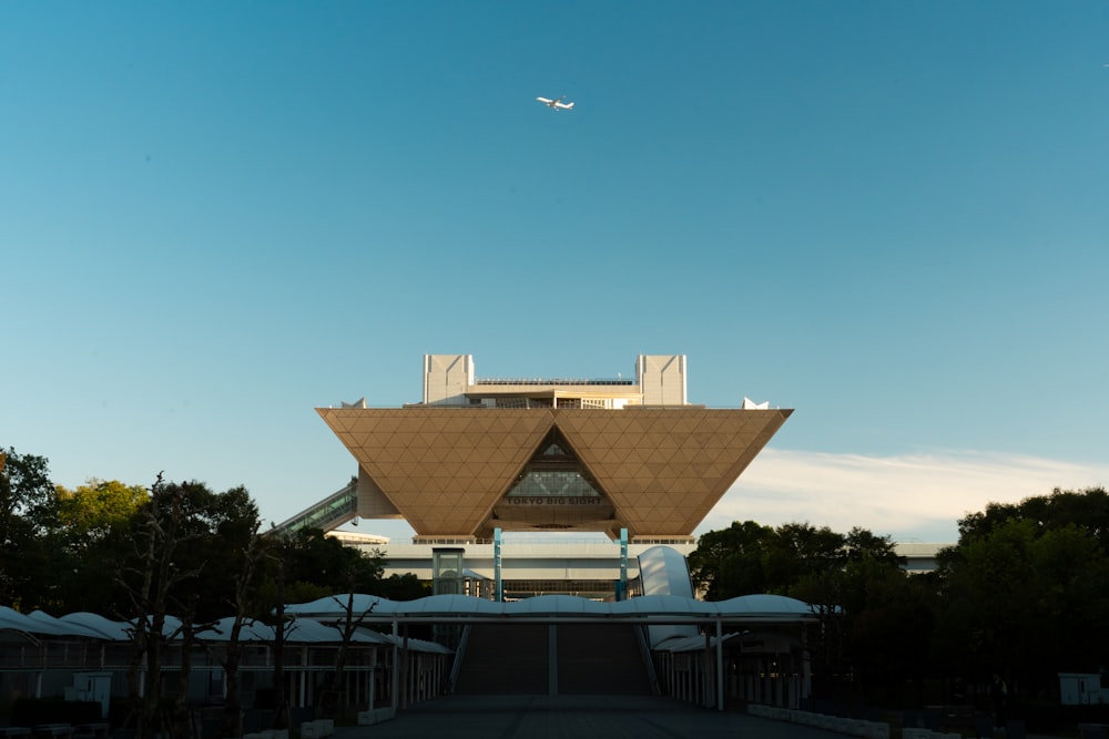 a large building with a plane flying over it