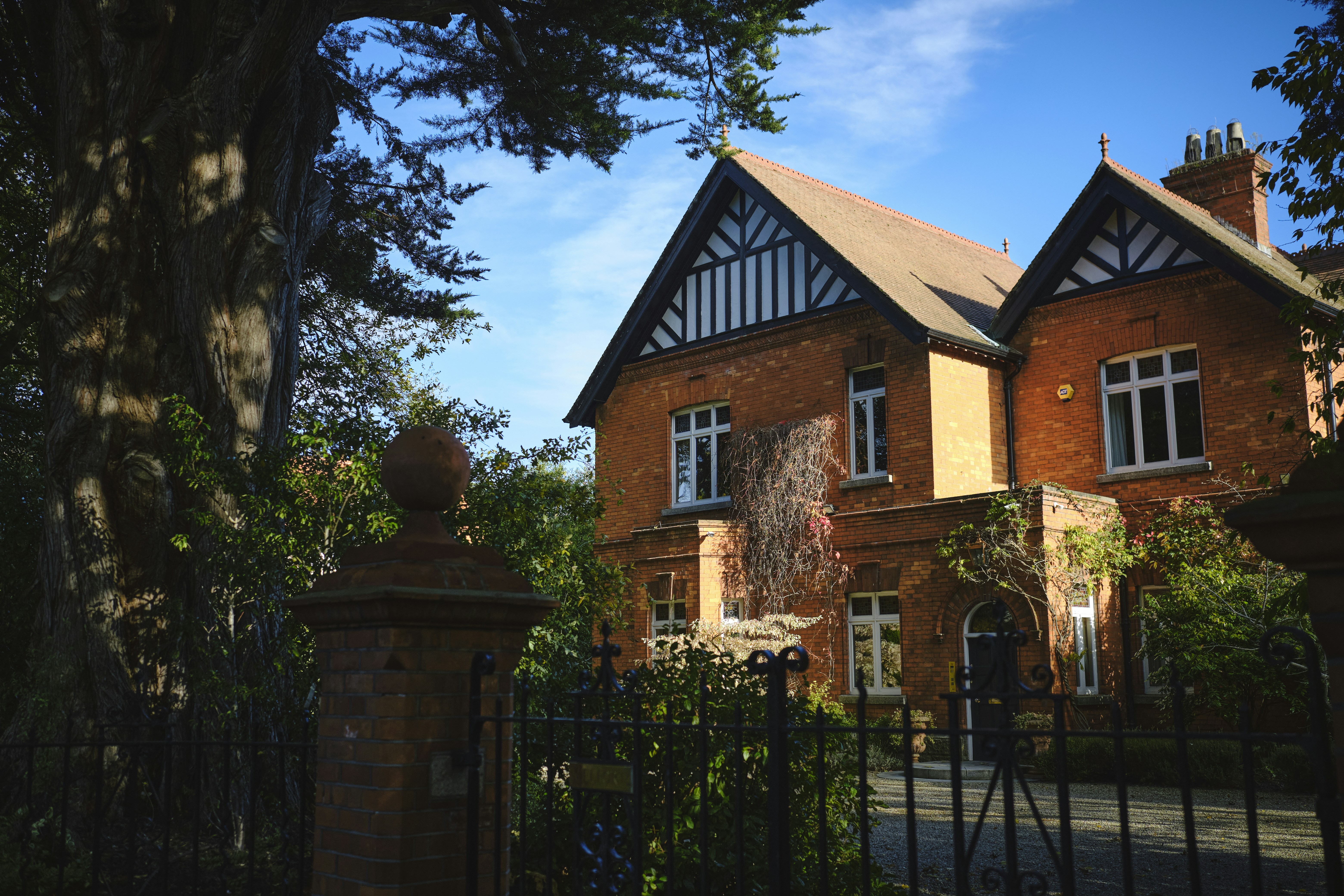 Large brick estate home with gabled roof and mature trees in Atherton, California.