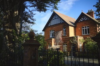 a large red brick house with a black iron fence