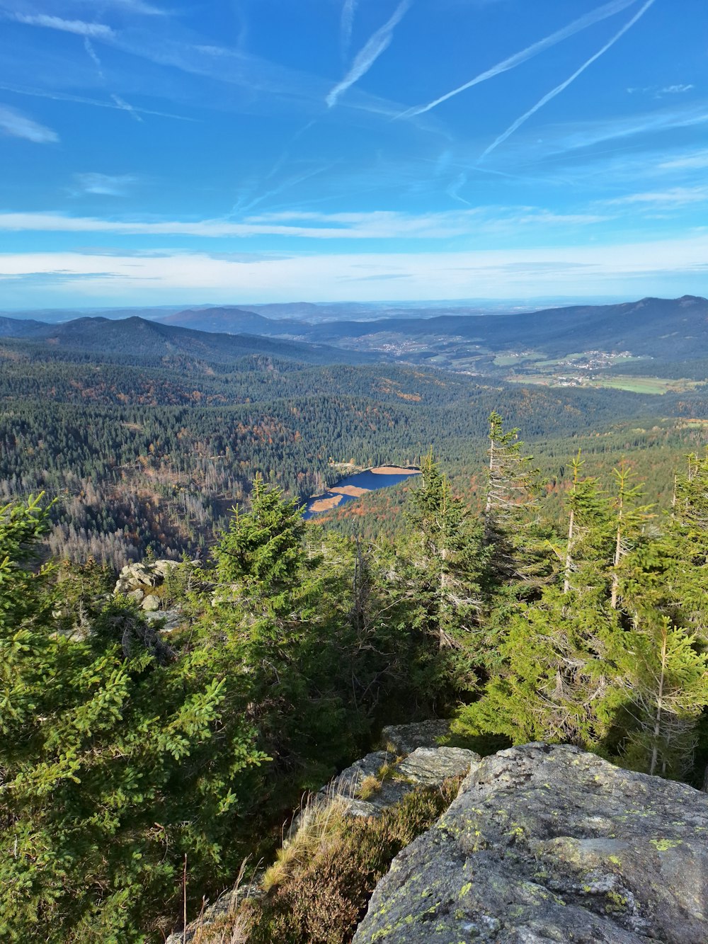 the view from the top of a mountain with a lake in the distance