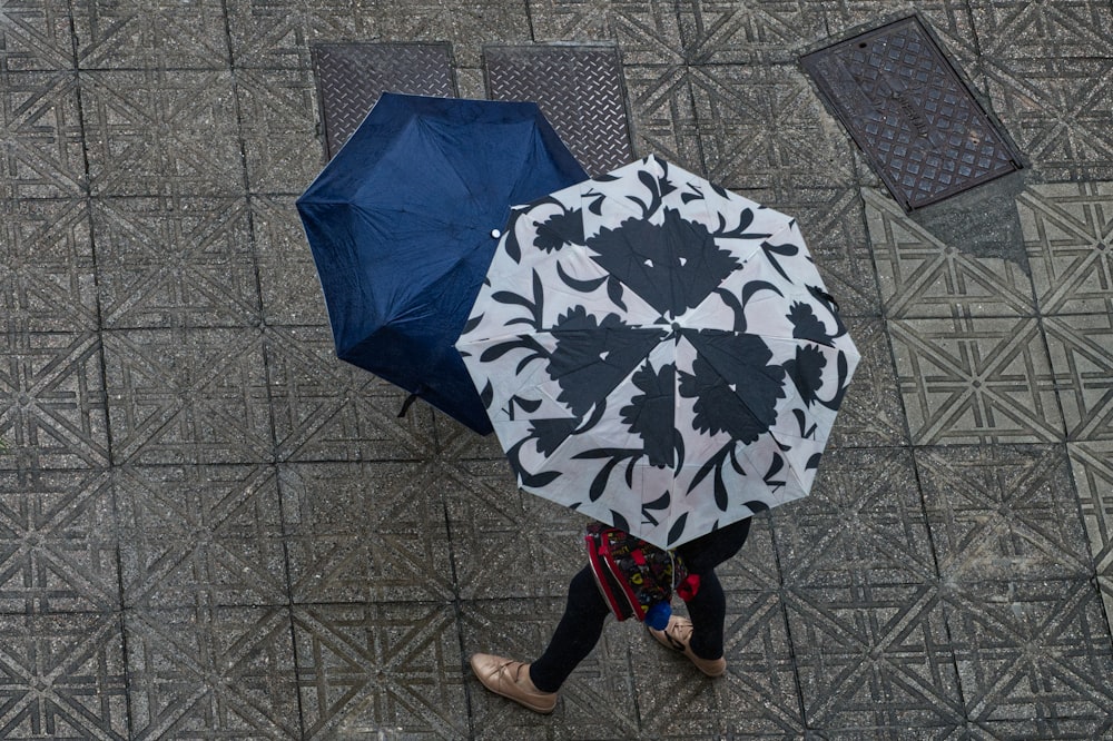 eine Person, die mit einem Regenschirm in der Hand eine Straße entlanggeht