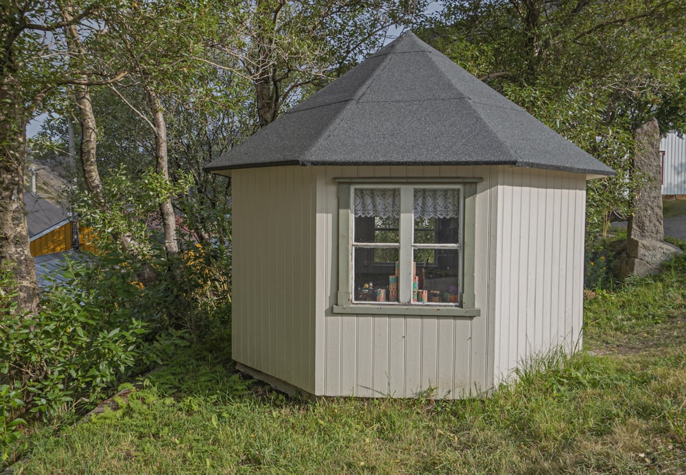 a small outhouse in the middle of a grassy area