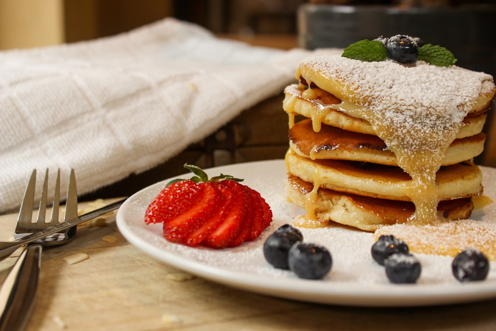 a stack of pancakes covered in powdered sugar and blueberries