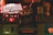 A dimly lit bar or pub interior with various vintage-style beer and liquor advertisements on wooden crates. Prominent brands like Desperados and Voll-Damm are visible, along with other labels. A no-smoking sign is displayed as well. The overall setting is rustic and nostalgic.