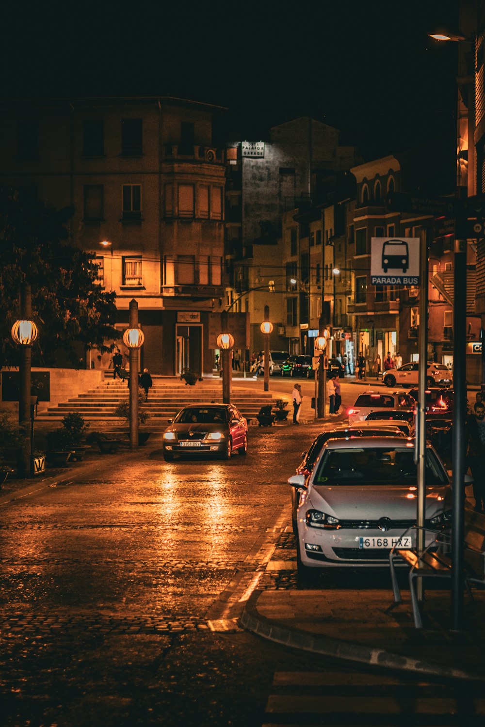 a city street at night with cars parked on the side of the road