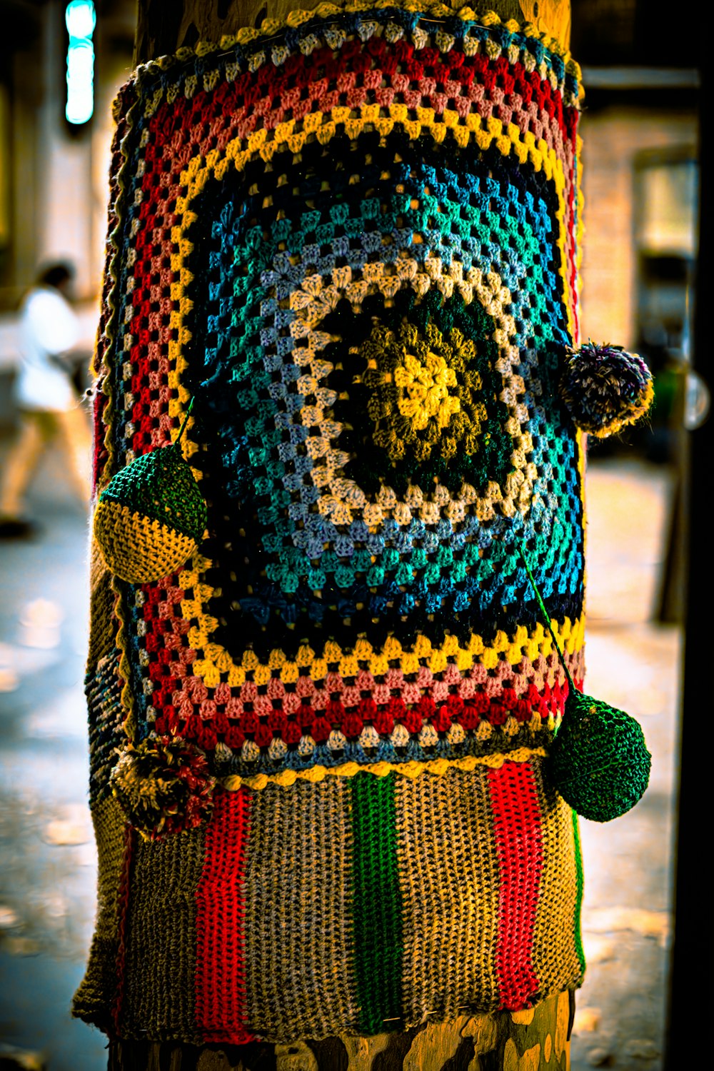 a multicolored crocheted bag hanging from a pole