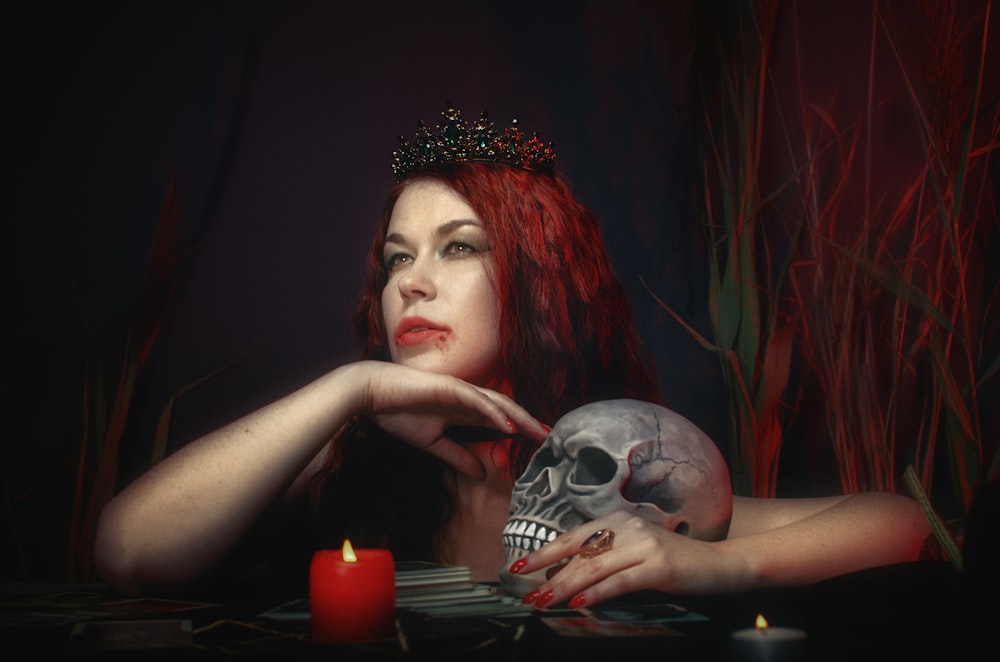 a woman with red hair is holding a skull