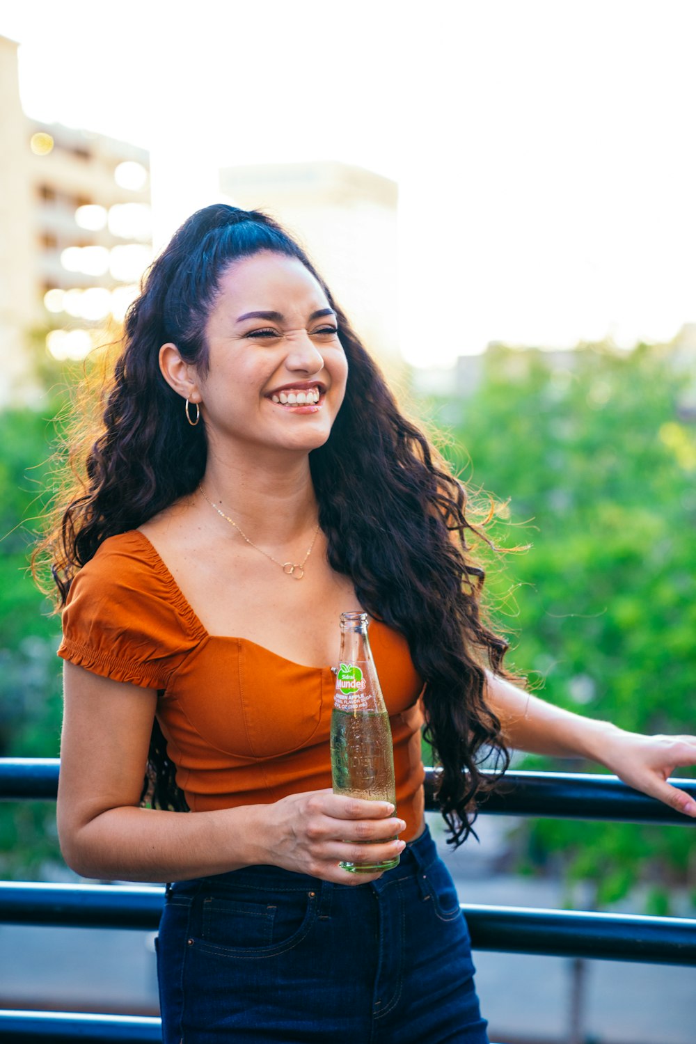 a smiling woman holding a bottle of beer