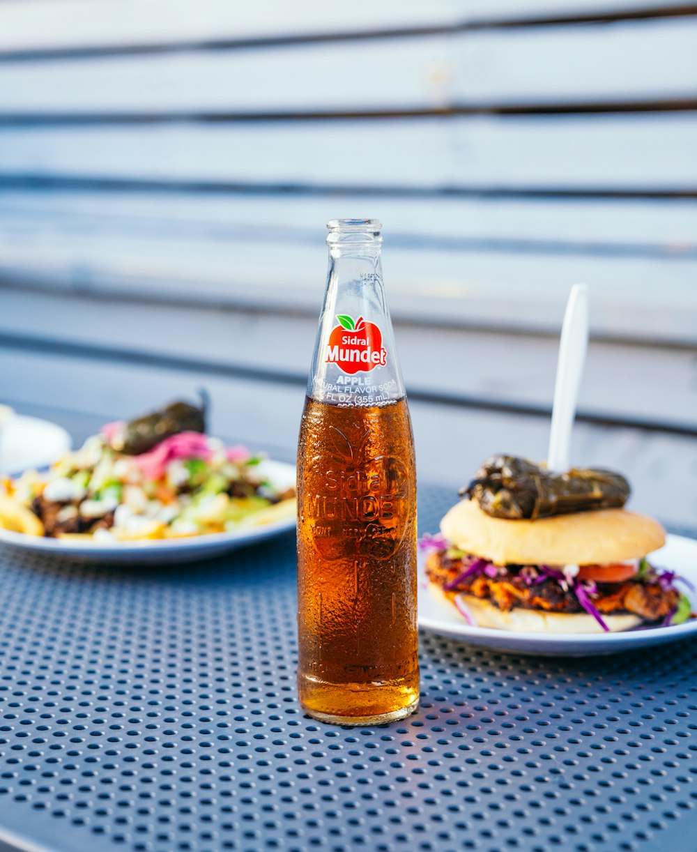 a table topped with plates of food and a bottle of soda