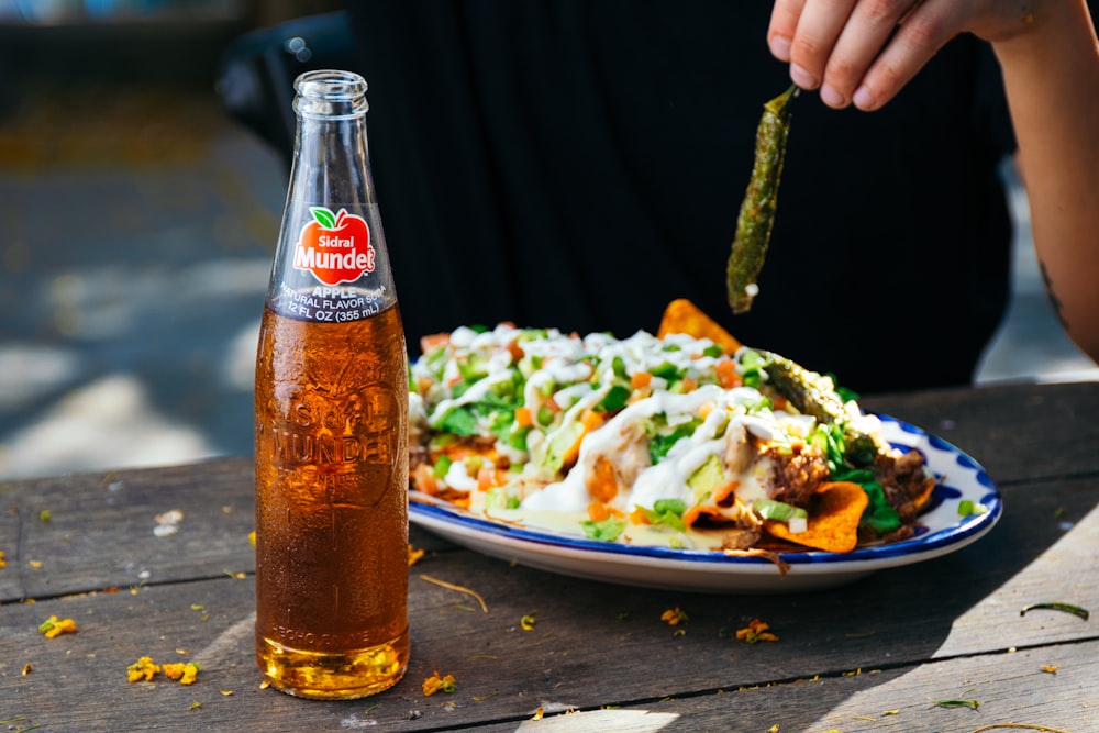 ein Teller mit Essen und eine Flasche Limonade auf einem Tisch